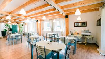 Un vaste espace dédié à la salle à manger, avec des poutres en bois, de nombreuses tables et des chaises.