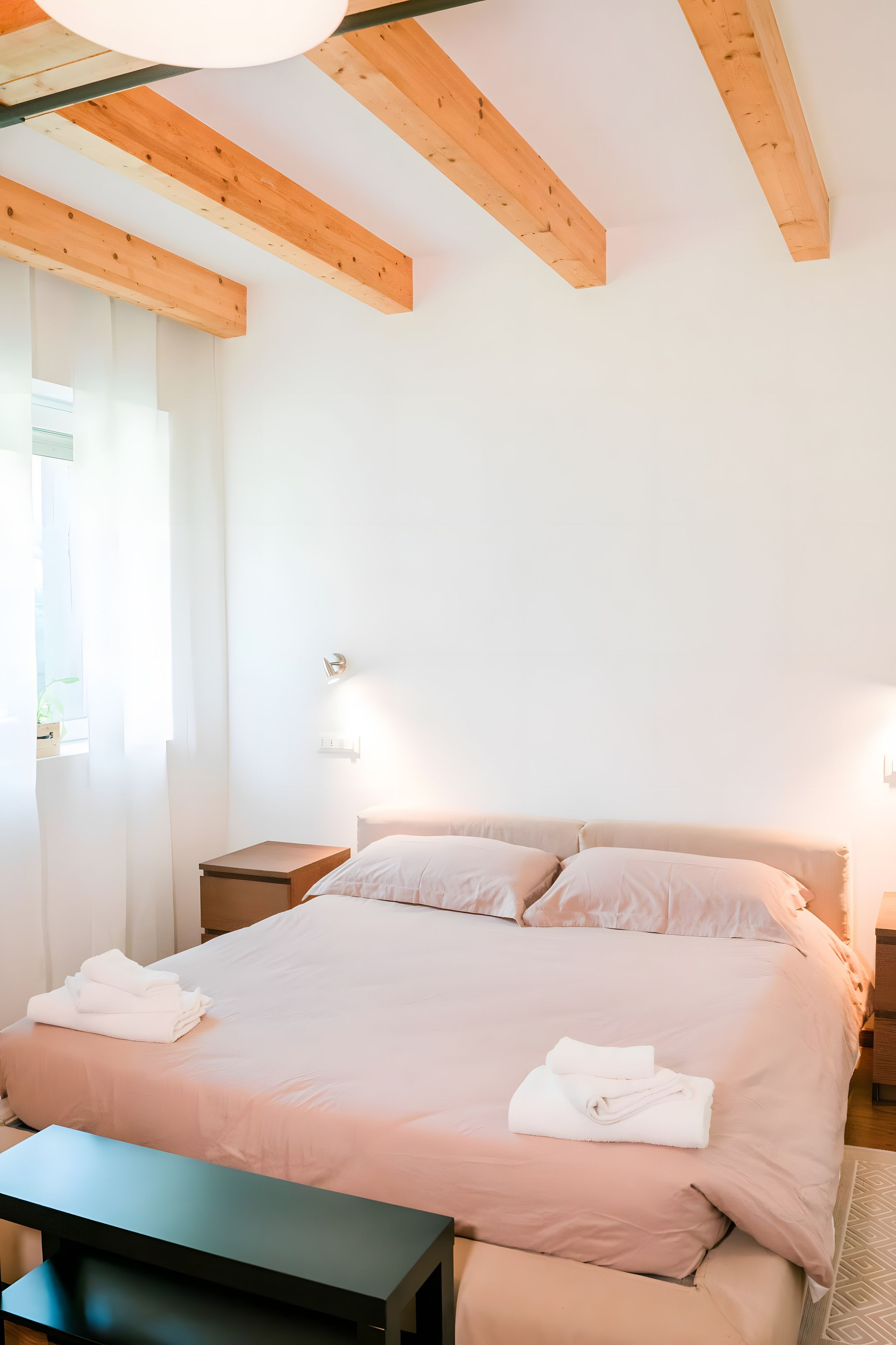 Un dormitorio con cama, mesitas de noche y una ventana.