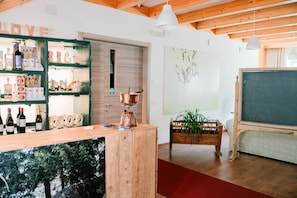 Un espace bar avec des étagères en bois où sont exposées des bouteilles et des verres, un pot en cuivre posé sur un présentoir et une moquette rouge.