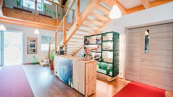Una habitació àmplia amb una escala de fusta, una zona de bar amb prestatges i una catifa vermella.