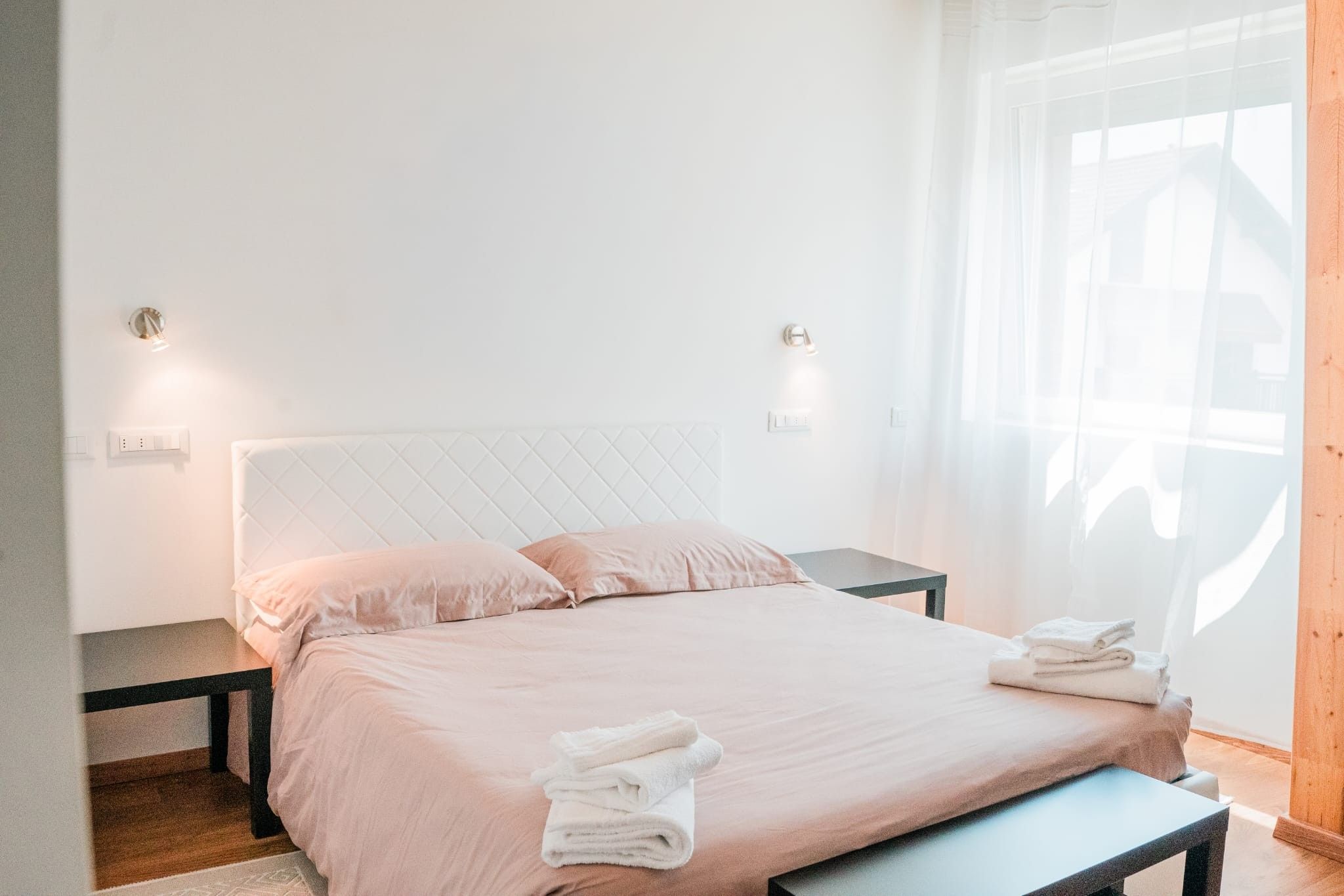 Ein Schlafzimmer mit einem Bett, Nachttischen und einem Fenster mit Vorhängen.