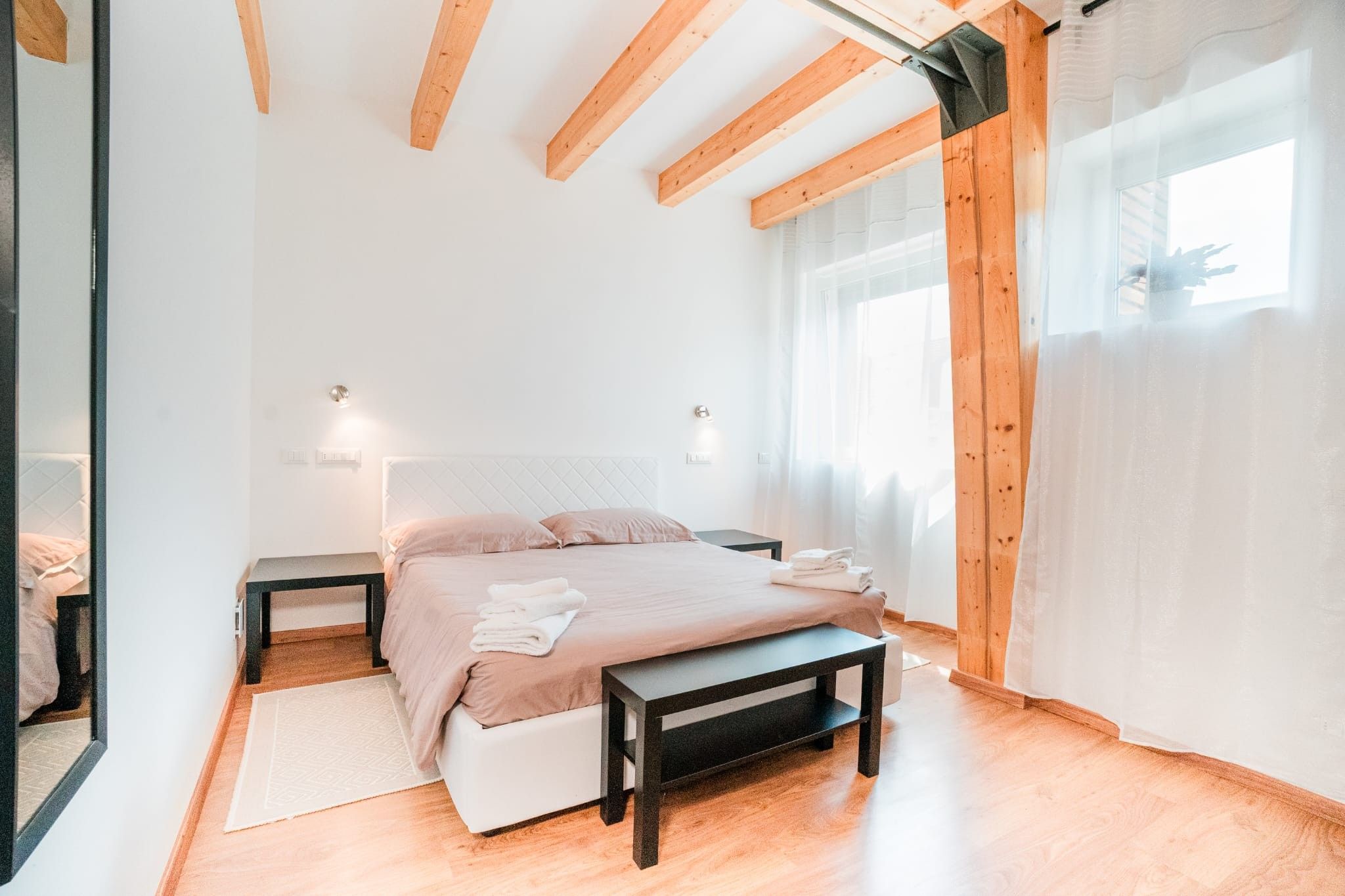 Une chambre à coucher moderne avec un lit, des tables de chevet et un banc.