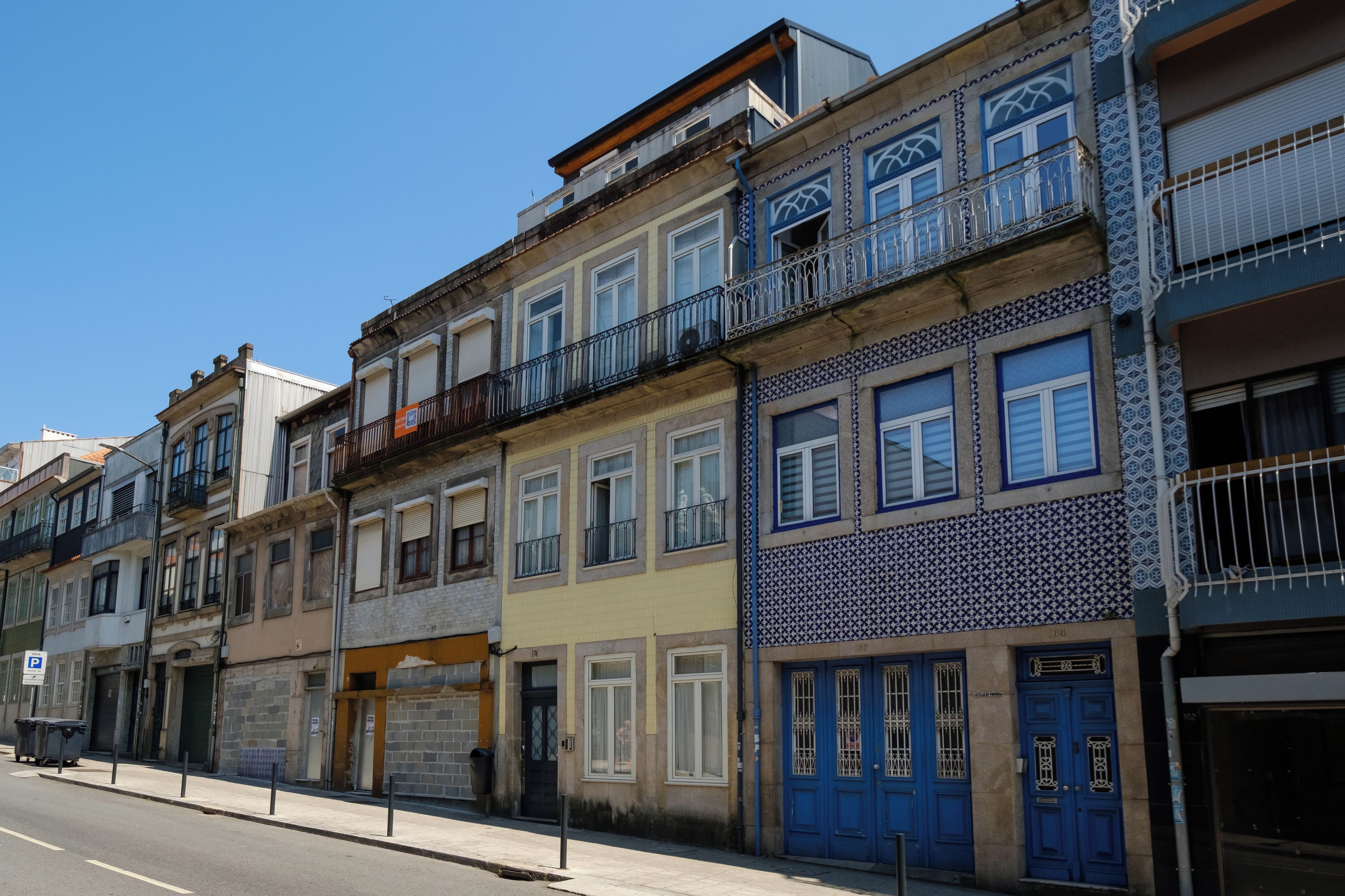 Eine Reihe mehrstöckiger Gebäude mit Balkonen, eine Straße davor und ein klarer Himmel.