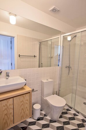 A modern bathroom with a glass shower enclosure, a white sink, and a toilet. - Apartment Bonfim w balcony metro station (Porto)