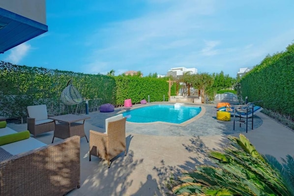 A swimming pool area with lounge chairs and a pergola.