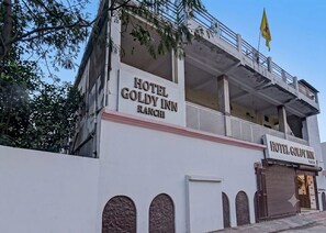 Un hotel llamado 'Hotel Goldy Inn Ranchi' con un letrero, un balcón y una bandera.