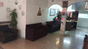 A reception area with a dark brown sofa, a potted plant, and a wall with hexagonal decorations.