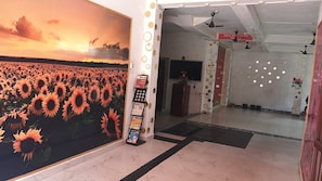 Zona de recepción con un mural de girasoles, mostrador de recepción y un cartel que indica la recepción.
