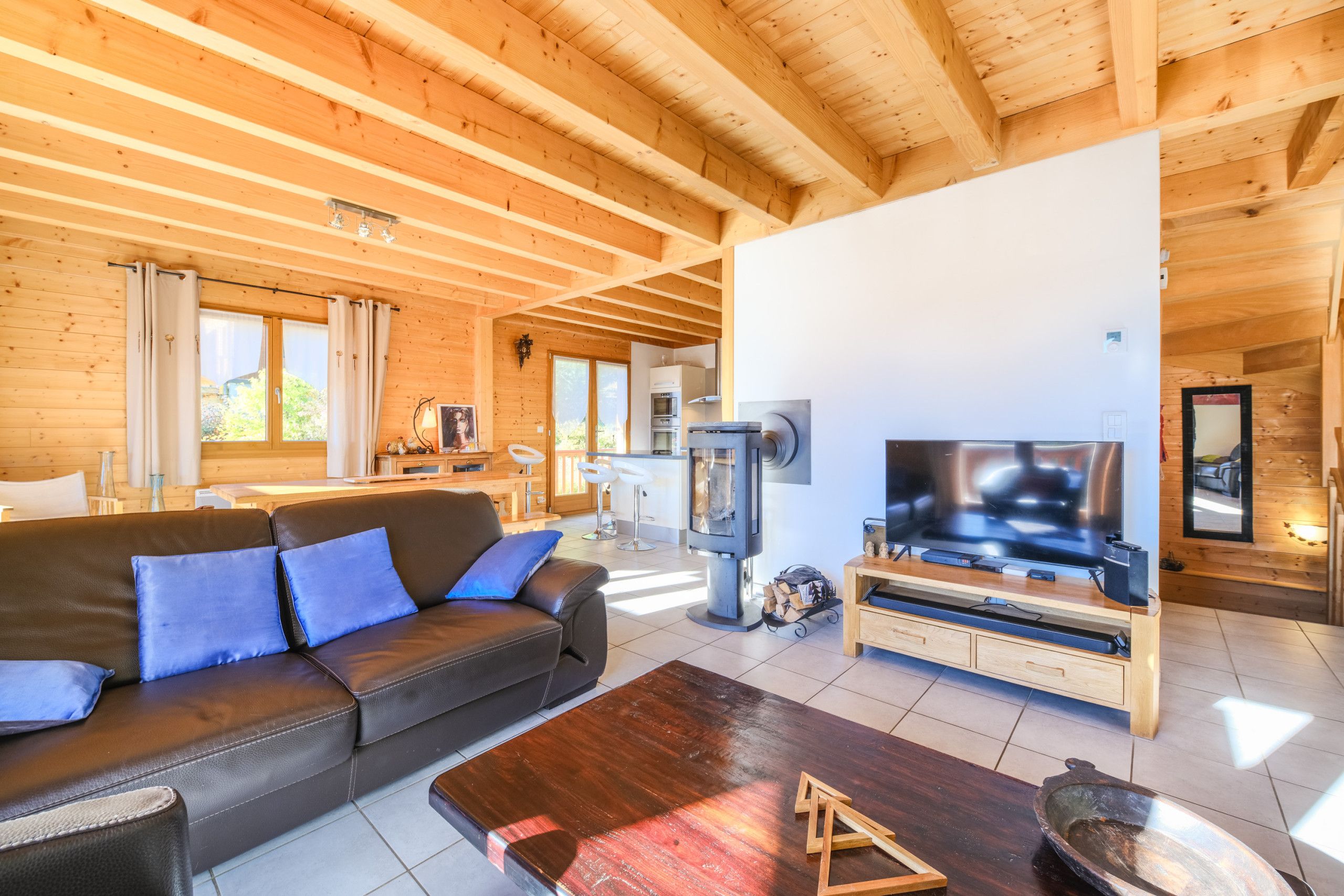 Un salon chaleureux avec un canapé en cuir, une table basse en bois, une cheminée et un téléviseur.