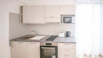A compact kitchen with a sink, stove, microwave, and a small countertop area.