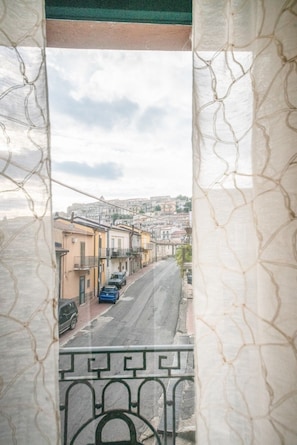 A balcony with a view of a street with buildings and parked cars.