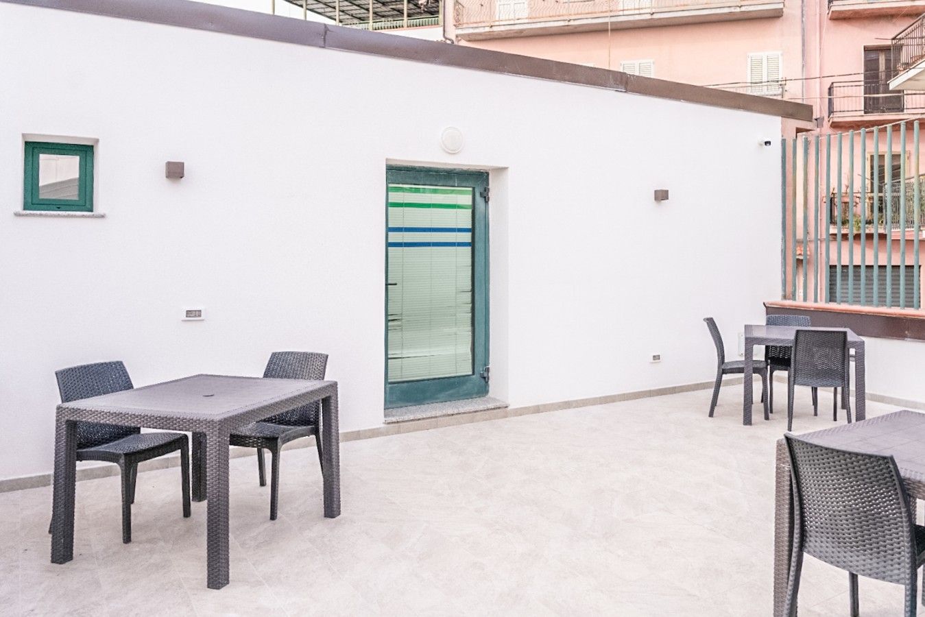Un espace patio avec une table et des chaises, une porte avec une fenêtre et un mur blanc.