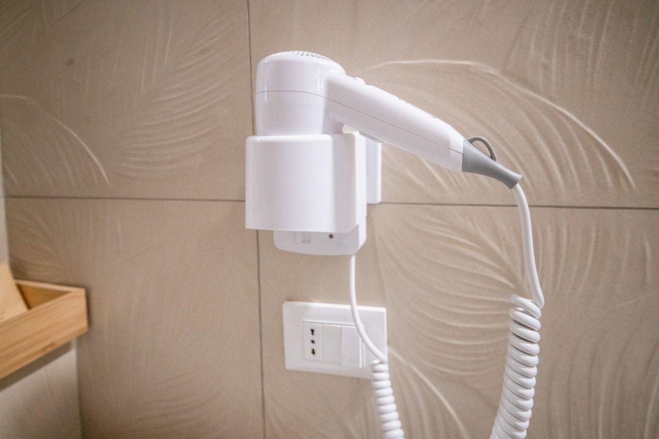 Un secador de pelo fijado a la pared con un cable enrollado.