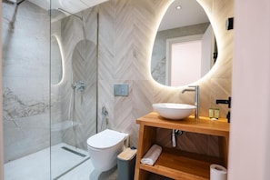 Un bagno moderno con cabina doccia in vetro, un water bianco e un mobile vanitario in legno con un lavandino grande.