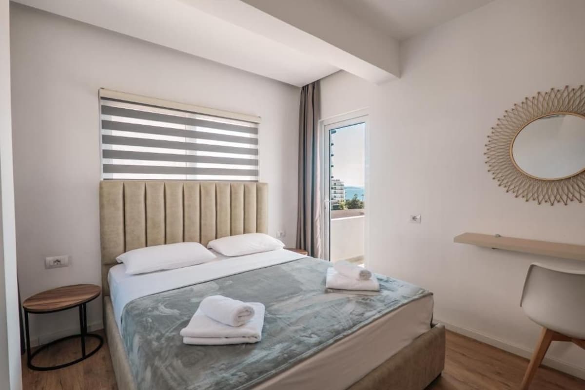 Una camera d'albergo con un letto, uno specchio rotondo, un tavolino e vista all'esterno.
