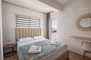 Una camera d'albergo con un letto, uno specchio rotondo, un tavolino e vista all'esterno.