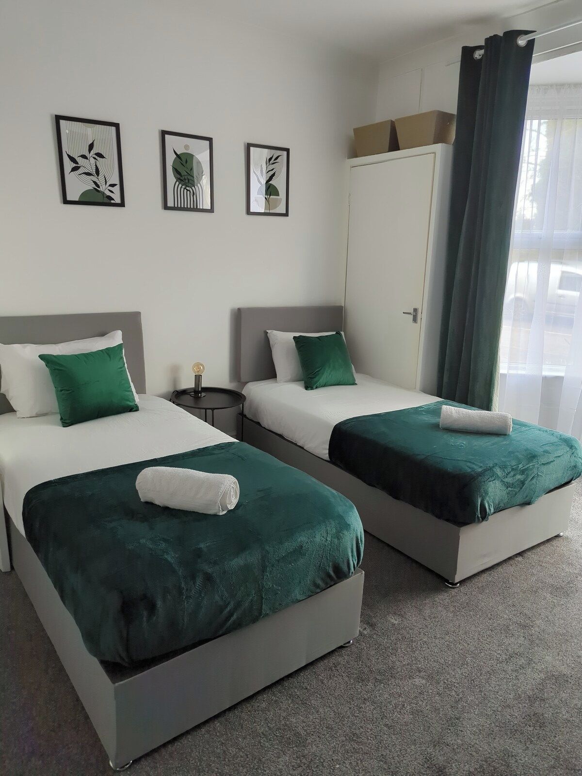 A hotel room with two beds, a wardrobe, and a nightstand.