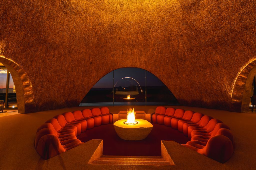 A circular seating area with a central fire feature, surrounded by a textured wall and arched openings.