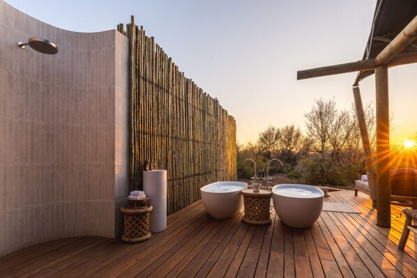 A wooden deck with three hot tubs, a shower, and a bamboo wall.