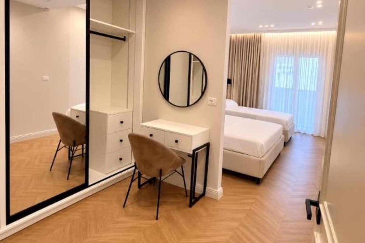Een moderne slaapkamer met een grote spiegel, een bureau en een bed.