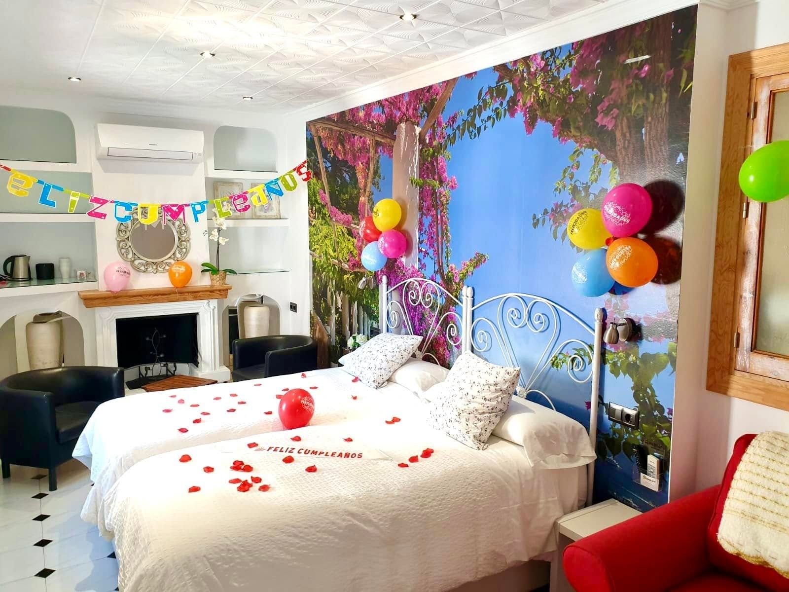 A bedroom with a bed, pillows, a wall mural, and a string of balloons.