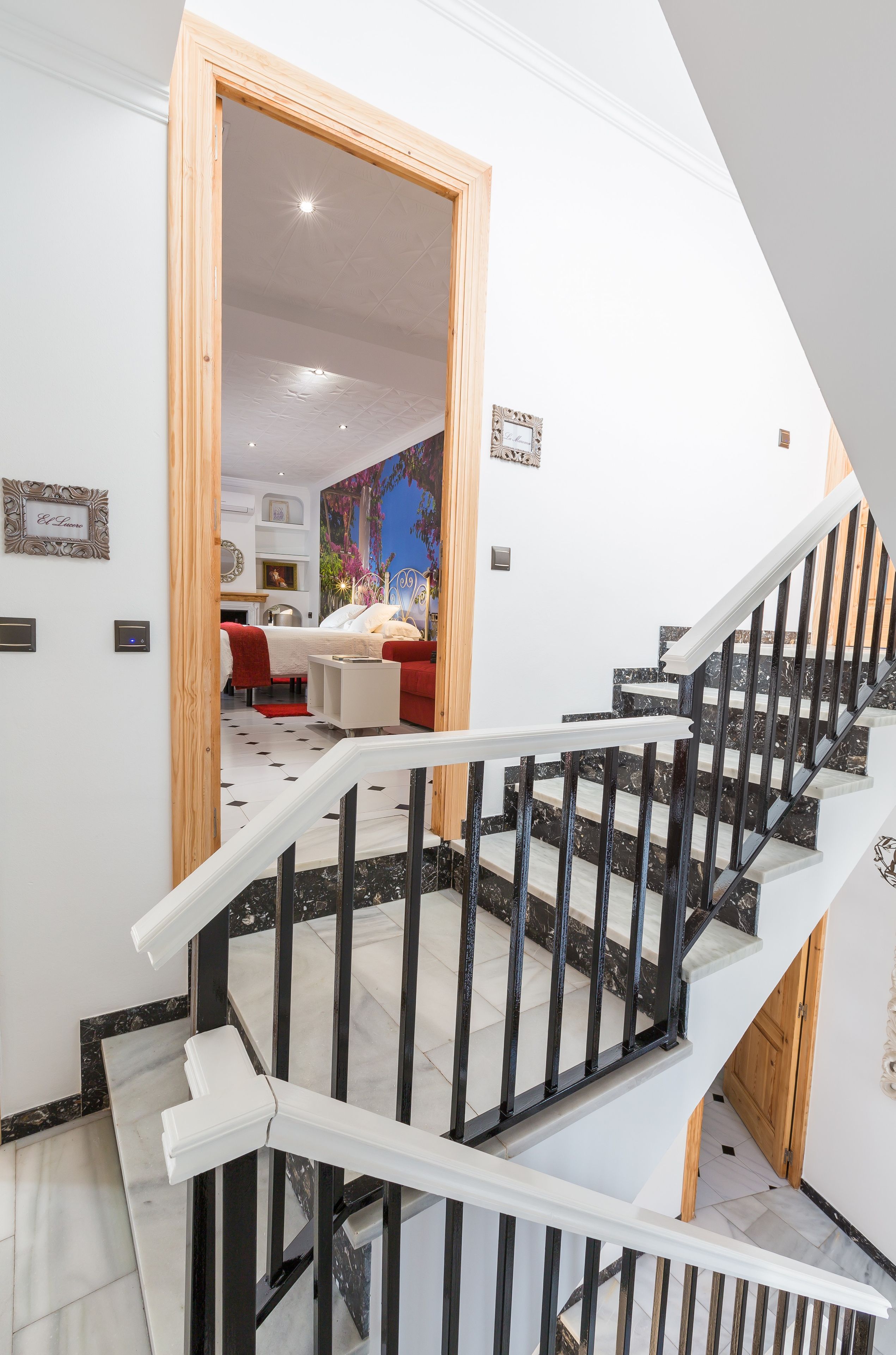 Una escalera con diseño blanco y negro que lleva a una habitación con una cama y una silla roja.