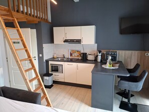 Cozinha compacta com forno embutido, cafeteira e torradeira.