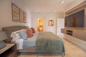Un dormitorio moderno con cama, televisor y obras de arte en la pared.