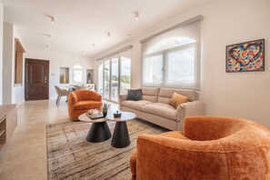 Amplia sala de estar con un sofá grande, dos sillones, una mesa de centro y un comedor con mesa y sillas.