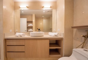 Un baño moderno con un espejo grande, un lavabo redondo y un inodoro.