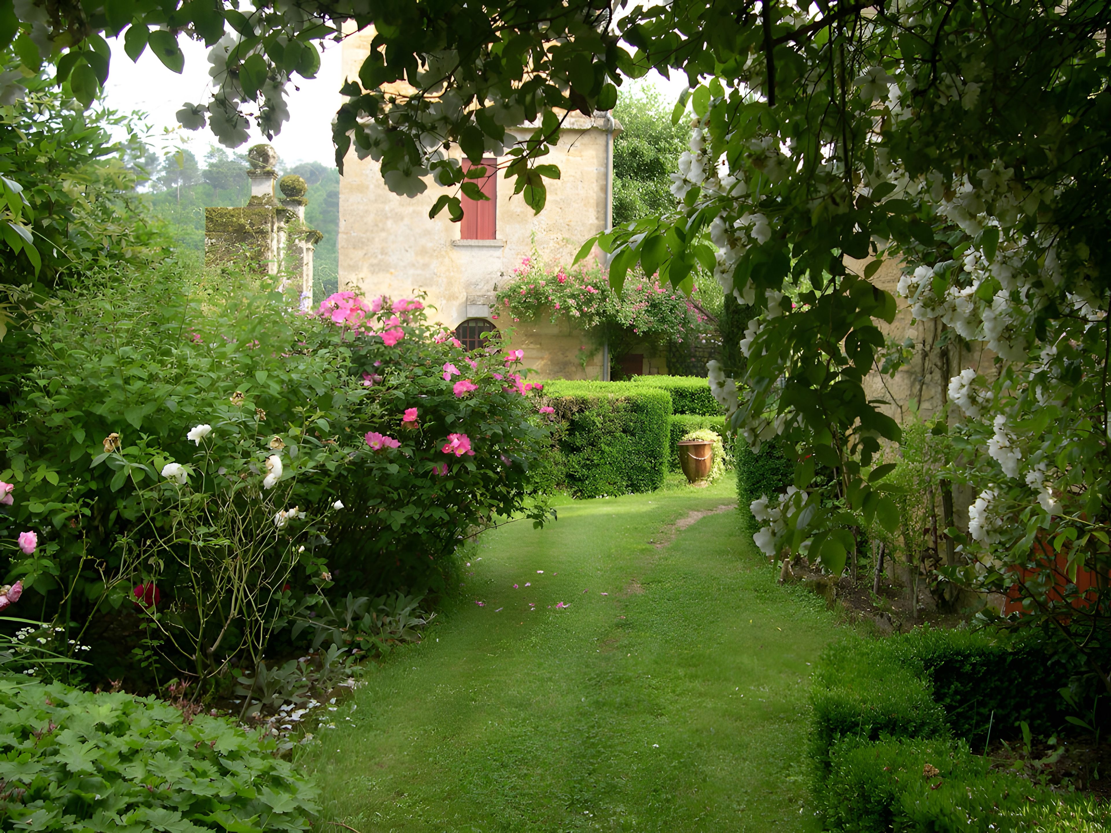 A well-maintained garden with a variety of flowering plants and a neatly trimmed hedge.