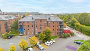 A multi-story building with a parking lot in front. - Stylish 2-Bed, 2-Bath Flat with Balcony & Parking (Warrington)