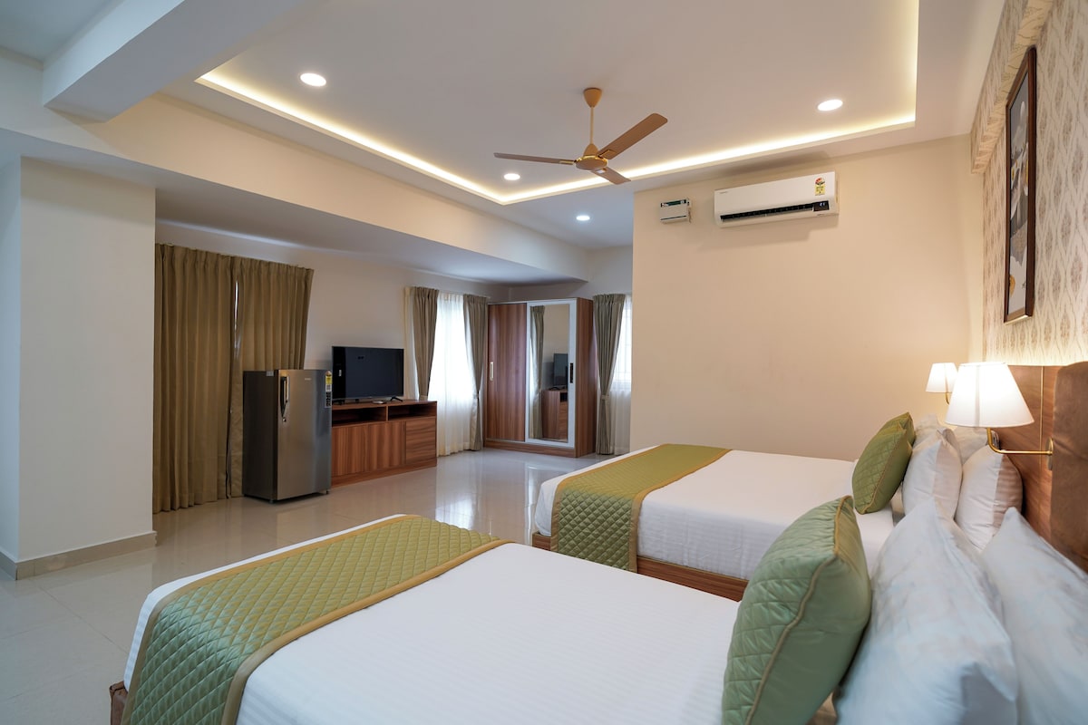 A hotel room with two beds, a television, a refrigerator, and an air conditioning unit.