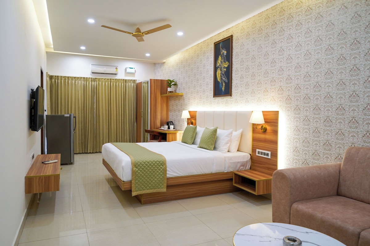 A hotel room with a bed, bedside table, lamp, and a television on the wall.