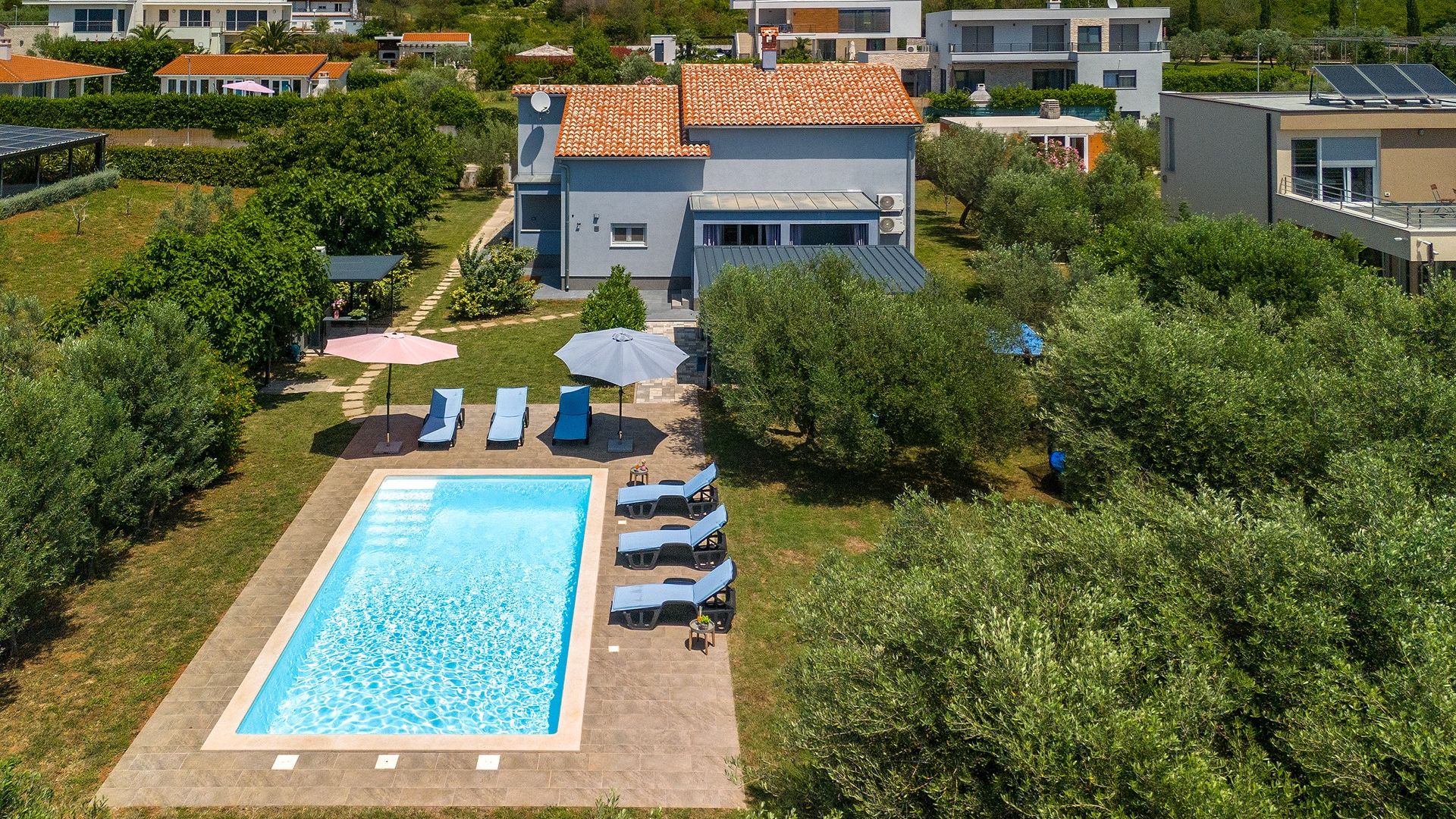 A residential property with a swimming pool, lounge chairs, and a garden area.