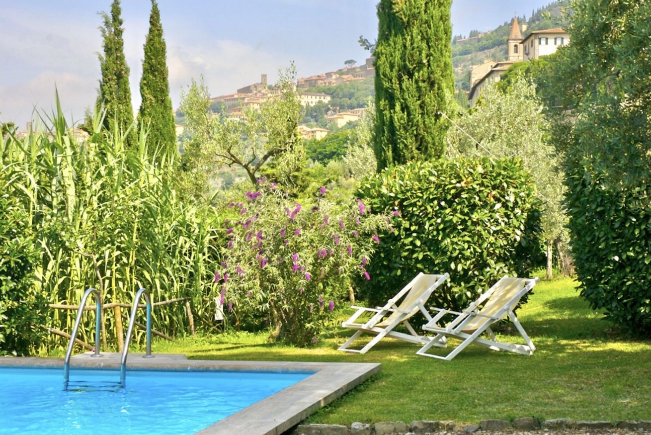 A swimming pool with a grassy area and two lounge chairs.