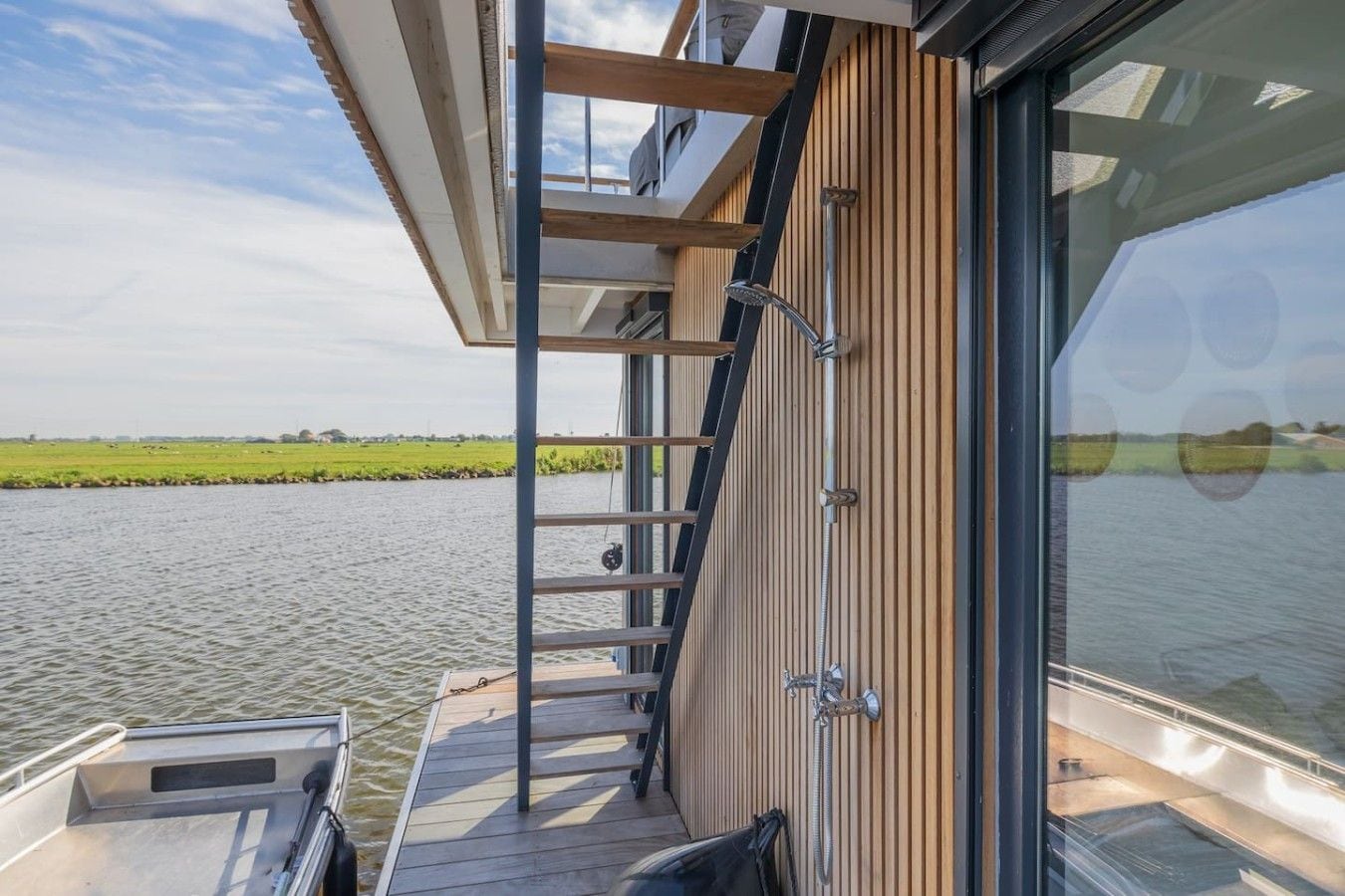 A boat with a wooden deck, metal railings, and a view of a calm water body.
