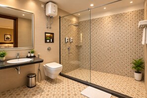 Un baño moderno con ducha de vidrio, lavamanos con espejo y azulejos estampados.