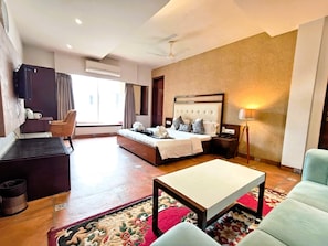 Habitación de hotel con cama, escritorio, silla, televisión y ventana.