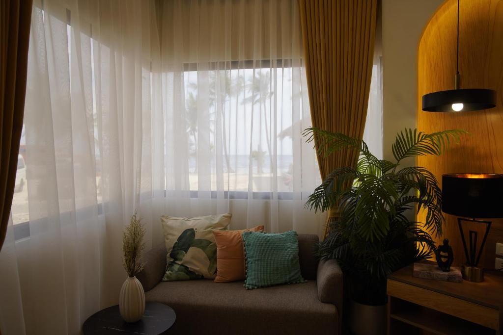 Una habitació amb un sofà, una taula auxiliar, una làmpada i una planta gran.