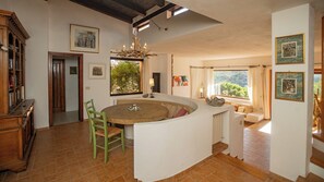 A spacious kitchen with a central island, wooden cabinets, and a view of the outdoors. - Kind & Secret:  villa with pool and panoramic rooftop terrace (Costa Paradiso)