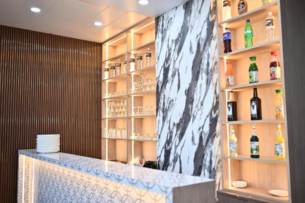 Eine Bar mit Regalen voller Flaschen und Gläsern, einer Wand mit Marmorverkleidung und einer Musterarbeitsplatte.