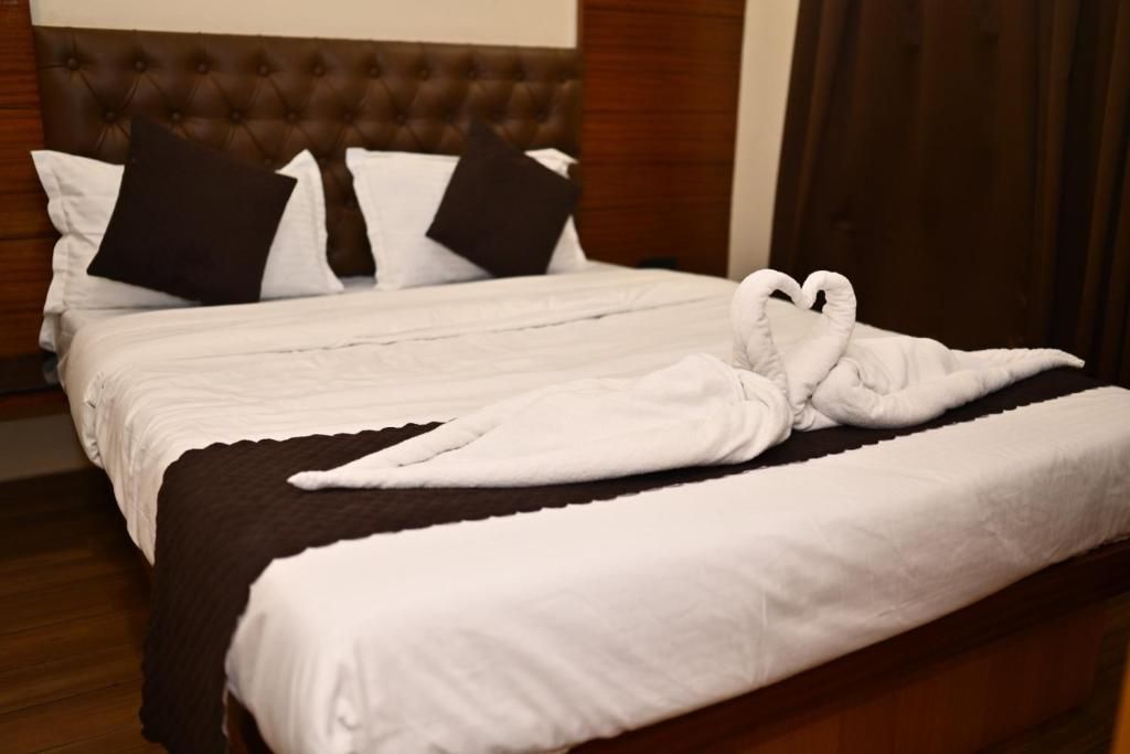 A neatly made bed with white linens and a brown headboard.