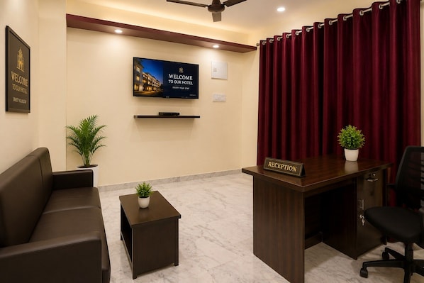 A hotel reception area with a reception desk, a sofa, a television displaying a welcome message, and a red curtain. - Hotel O Boby Royal Palace (Patti)