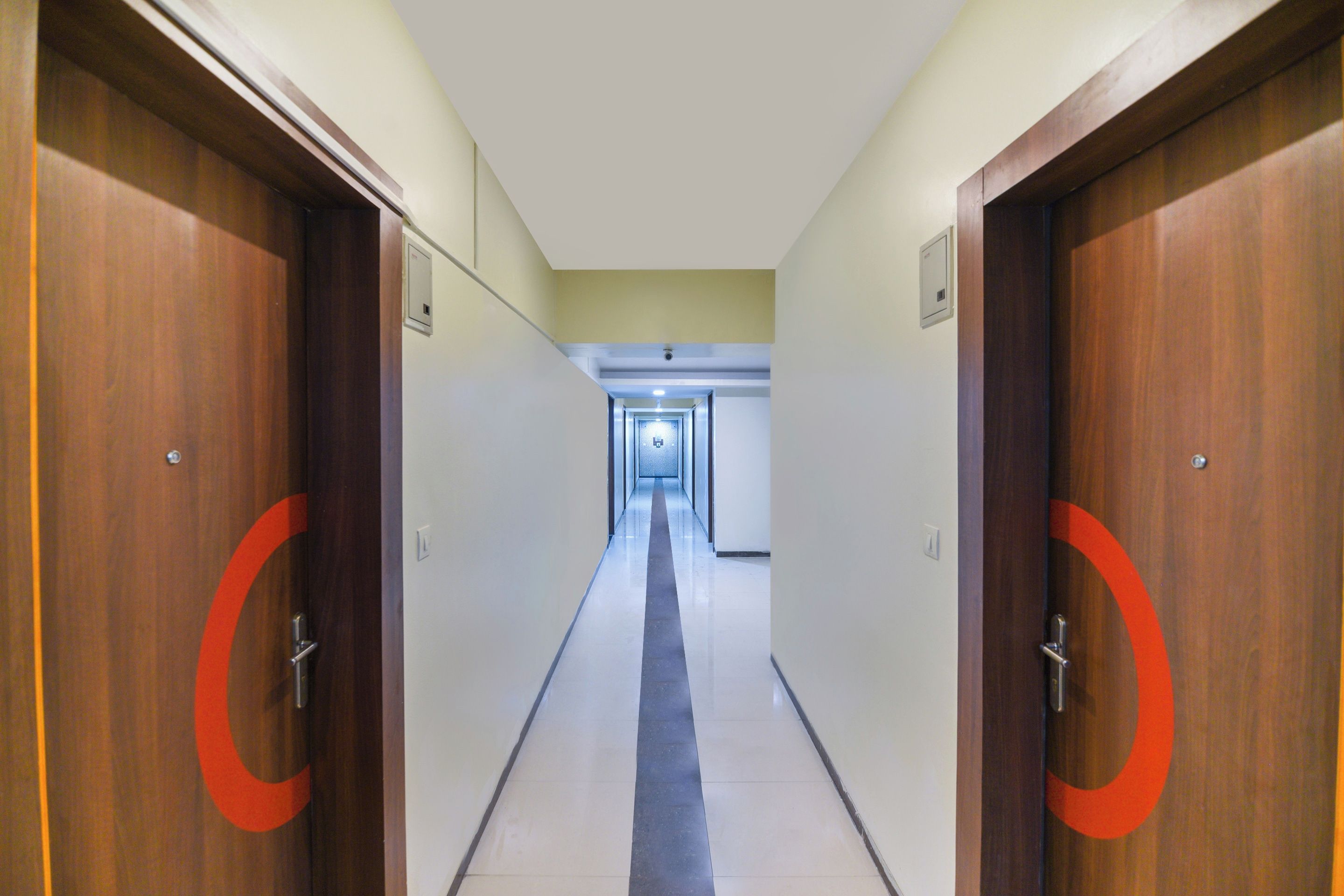 A hotel corridor with wooden doors and a tiled floor.