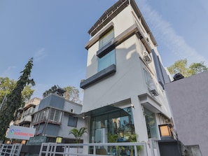 A hotel with a modern design, featuring a prominent glass facade and a balcony. - Hotel O Sunshine Inn Near Pune Railway (Pune)