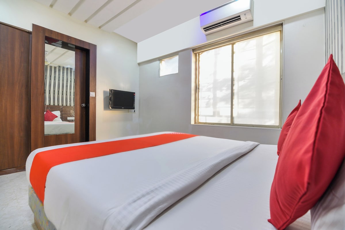 A hotel room with a bed, a television, a window, and a door.