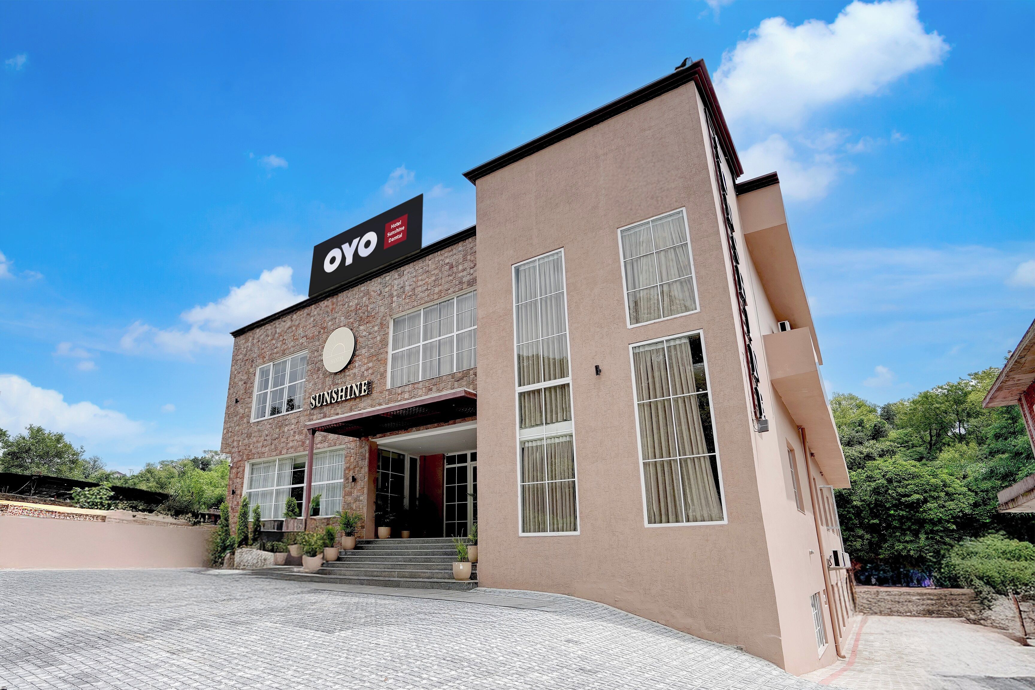 Un hotel con un letrero que dice 'OYO Sunshine Damtal' y una placa con el nombre 'SUNSHINE'.