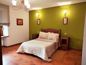 A bedroom with a bed, nightstands, a chandelier, and wall-mounted lights. - Country House 'Casa Rural El Robledo' with Private Terrace and Private Garden (Muñotello)