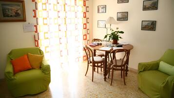 Une pièce comprenant une table à manger, des chaises, une plante en pot et des œuvres d’art accrochées aux murs.